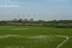 Power plant with green field againts sky photo