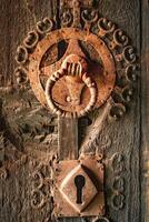 Old, Antique, Vintage and Retro rusty door lock with handle mounted on weathered wooden door photo