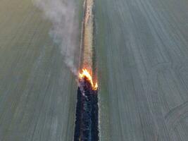 ardiente seco césped a lo largo el irrigación canal. fumar y el fuego de seco césped. quemado seco césped. foto