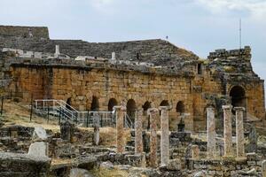 Ancient antique amphitheater in city of Hierapolis in Turkey. Side view. Steps and antique statues with columns in the amphitheater photo