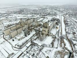 Sprinkled with snow grain elevator. Winter view of the old Soviet elevator. Winter view from the bird's eye view of the village. The streets are covered with snow photo