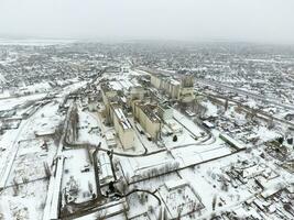 Sprinkled with snow grain elevator. Winter view of the old Soviet elevator. Winter view from the bird's eye view of the village. The streets are covered with snow photo