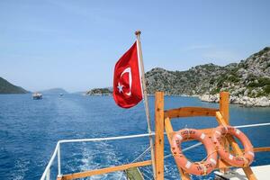 Turkey flag at the stern of a pleasure yacht. View of Mediterranean coast photo