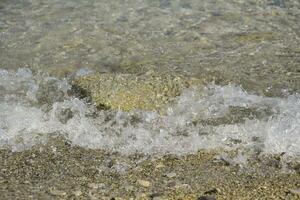 mar olas correr en tierra, burbujeante y Roca cubierta foto