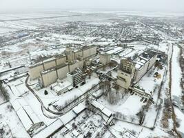 Sprinkled with snow grain elevator. Winter view of the old Soviet elevator. Winter view from the bird's eye view of the village. The streets are covered with snow photo