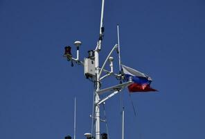 Mast of the port service ship. Devices of light signaling and communication antenna. photo