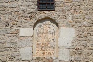mortgaged window in the mosque. Window with inscriptions. A wall of limestone and cement. photo