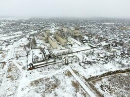 Sprinkled with snow grain elevator. Winter view of the old Soviet elevator. Winter view from the bird's eye view of the village. The streets are covered with snow photo