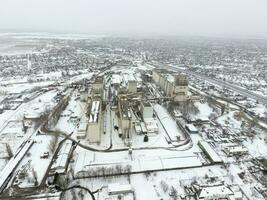 Sprinkled with snow grain elevator. Winter view of the old Soviet elevator. Winter view from the bird's eye view of the village. The streets are covered with snow photo