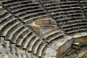 steps of the amphitheater. Stone limestone and marble. Ancient antique amphitheater in city of Hierapolis in Turkey. Steps and antique statues with columns in the amphitheater photo