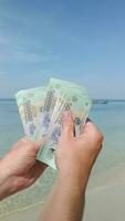 Hands counting Vietnamese Dong on tropical beach in Vietnam. Close up video