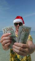 Man wearing Santa hat counting US dollars on tropical beach video