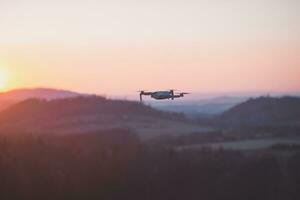 Mobile drone at work during sunset. Technological innovation in photography and aviation. Aerial view video recording. Flying device photo