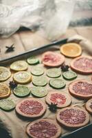 Sliced orange, tangerine and grapefruit slices on baking sheet, preparing citrus wedges for Christmas garland photo