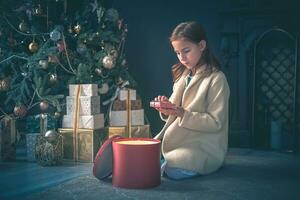 linda niña apertura presente siguiente a Navidad árbol. foto