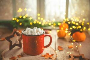 Cute cozy winter composition. red mug, marshmallows, oranges and Christmas lights. photo