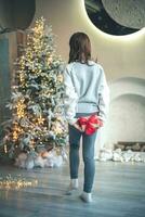 a girl carries a gift under the Christmas tree photo