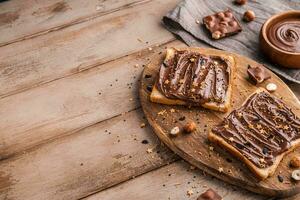 Board of bread with chocolate paste and hazelnuts on wooden background photo