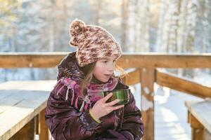 linda niña en invierno en escarchado clima bebidas caliente té desde un termo foto