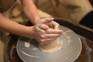 Potter girl works on potter's wheel, making ceramic pot out of clay in pottery workshop photo