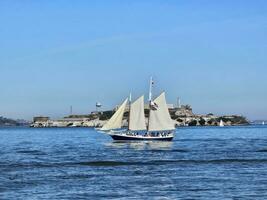 un vela barco cruce en frente de alcatraz isla en san francisco California foto