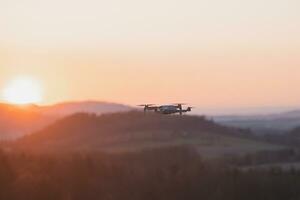 Mobile drone at work during sunset. Technological innovation in photography and aviation. Aerial view video recording. Flying device photo