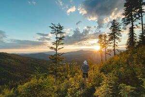 Enthusiastic hiker aged 50-55 with a hat standing on a stump watching the sunset in Beskydy mountains, Czech Republic. Hiking lifestyle photo