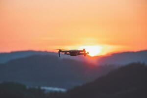 Mobile drone at work during sunset. Technological innovation in photography and aviation. Aerial view video recording. Flying device photo