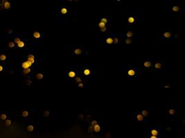 abstract bokeh yellow light orange and white glowing flare pattern black background photo