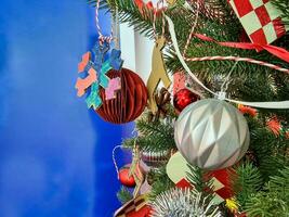 Happy new year cozy home interior with christmas tree and garlands small red and silver balls. blurred lights golden bokeh.Merry Christmas isolated on blue background. photo