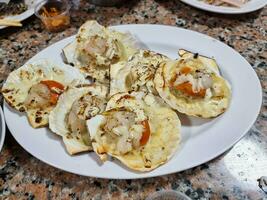 Garlic Scallops on white plate dining table. Seared Scallops With Brown Butter and Lemon Pan Sauce hot bbq. photo