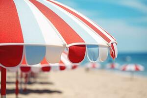 AI generated Close up image of a red blue and white vertical striped beach umbrella on a background of a beach with sun loungers and blue sea photo