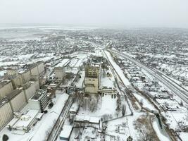 Sprinkled with snow grain elevator. Winter view of the old Soviet elevator. Winter view from the bird's eye view of the village. The streets are covered with snow photo