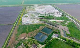 garbage dump with heaps of garbage and treatment facilities. Landfill of garbage outside the village photo