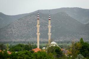 dos minaretes de un mezquita en el aldea. turco foto