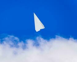 White paper airplane in a blue sky with clouds. The message symbol in the messenger photo