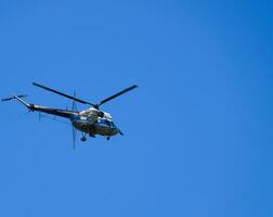 A helicopter of agricultural aviation is flying in the blue sky. photo