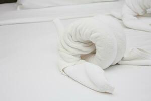 blanco toallas en el cama en el hotel habitación arrollado arriba en el forma de animales, hotel habitación, blanco cama en el hotel foto