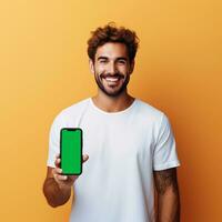 ai generado hermoso hombre participación un móvil teléfono con verde pantalla, aislado en amarillo degradado antecedentes foto