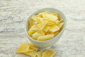 Sliced parmesan cheese heap in the bowl photo