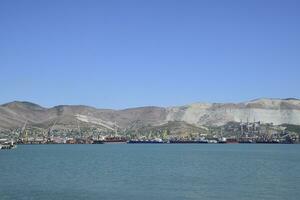 carga Puerto con Puerto grúas mar bahía y montañoso costa. foto
