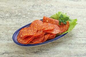 Sliced pepperoni sausage in the bowl photo