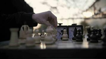 une échecs joueur se déplace le blanc pièces. en jouant échecs sur le rue. video