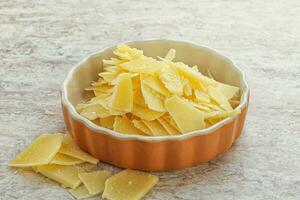 Sliced parmesan cheese heap in the bowl photo