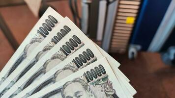 a person holding a stack of japanese currency photo