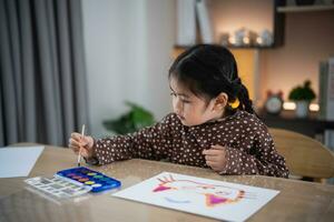 Cute little asian baby smiling painting with colorful paints using watercolor. Asian girl using paintbrush drawing color. Baby activity lifestyle concept. photo