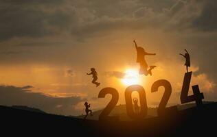 Woman jump happy new year 2024 concept, silhouette of woman jumping over barrier cliff and success with beautiful sunset background. Happy New Year 2023 use for web banner and advertisement. photo