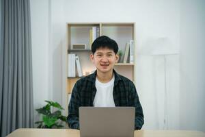 Smart Asian man with braces smiling working with computer laptop. concept work form home, stay at home. freelance life style, New normal social distancing lifestyle. Work form anywhere concept. photo