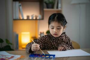 Cute little asian baby smiling painting with colorful paints using watercolor. Asian girl using paintbrush drawing color. Baby activity lifestyle concept. photo