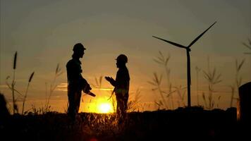 silhuett av ingenjör i avgift av vind energi mot en bakgrund av vind turbiner. hög fem efter slutföra dagligen uppgifter. video